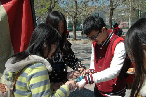 展台工作人员为活动参与同学盖宣传印章 展台工作人员为活动参与同学盖宣传印章