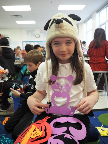 头戴熊猫帽子的艾比展示剪纸作品 头戴熊猫帽子的艾比展示剪纸作品